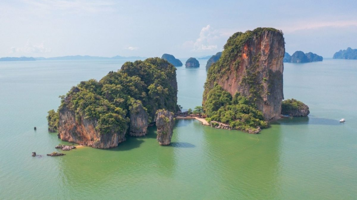 James Bond Island with iconic limestone rock formations and tour boats in Phang Nga Bay Thailand